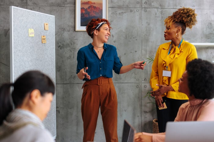 Diverse female business team collaborating on presentation during boardroom meeting.