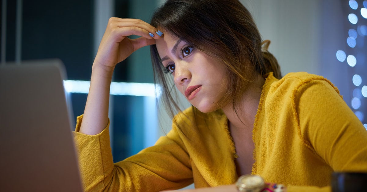 Hispanic woman using pc at work who is upset