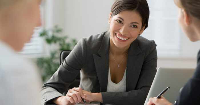 Smiling Canadian woman of Indigenous descent working with colleagues in an office setting.