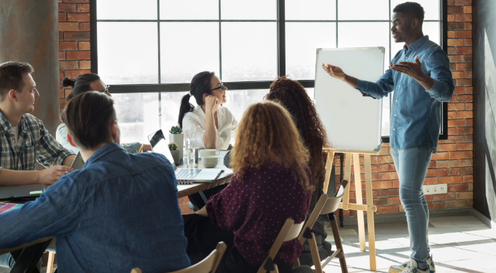 man with whiteboard speaking to colleagues