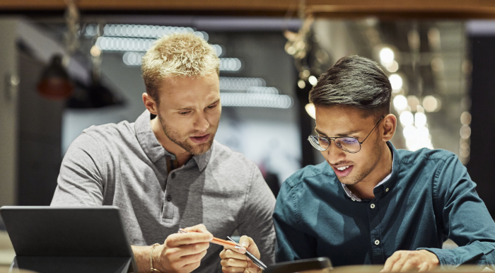 two men at desk discussing work